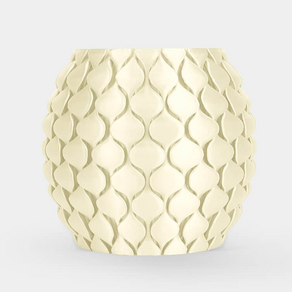 A round, textured ceramic planter or candle holder in a pale cream color, featuring a raised scale-like pattern, set against a solid light gray background.